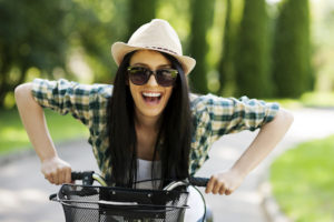 Woman riding a bike smiling after getting a tooth filled from the restorative dentistry menu at Sound to Mountain Dental in Tacoma, WA.