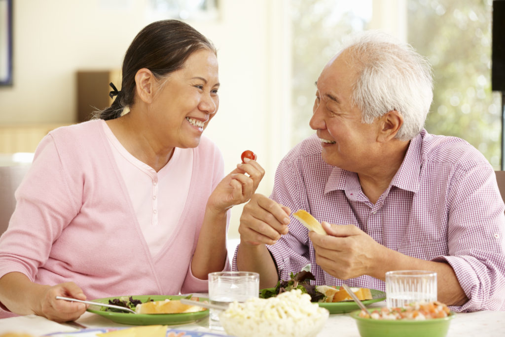 Older Asian couple eating with confidence because of the dental implants they received from Dr. Hickey at Sound to Mountain Dental in Tacoma, WA.