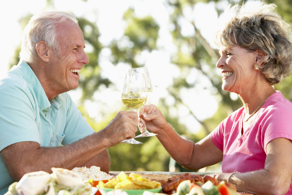 Elderly couple toasting that they have no worried because they have the best fit with the dentures they got from Dr. Hickey at Sound to Mountain Dental in Tacoma, WA.