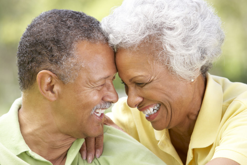 Older black couple smiling because they know they have perfectly fitted dentures from Sound to Mountain Dental in Tacoma, WA.