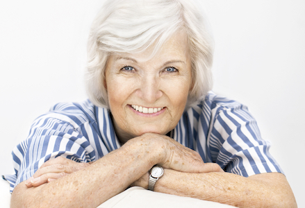 Older lady showing off her dental crown which you can't tell from her natural teeth. 